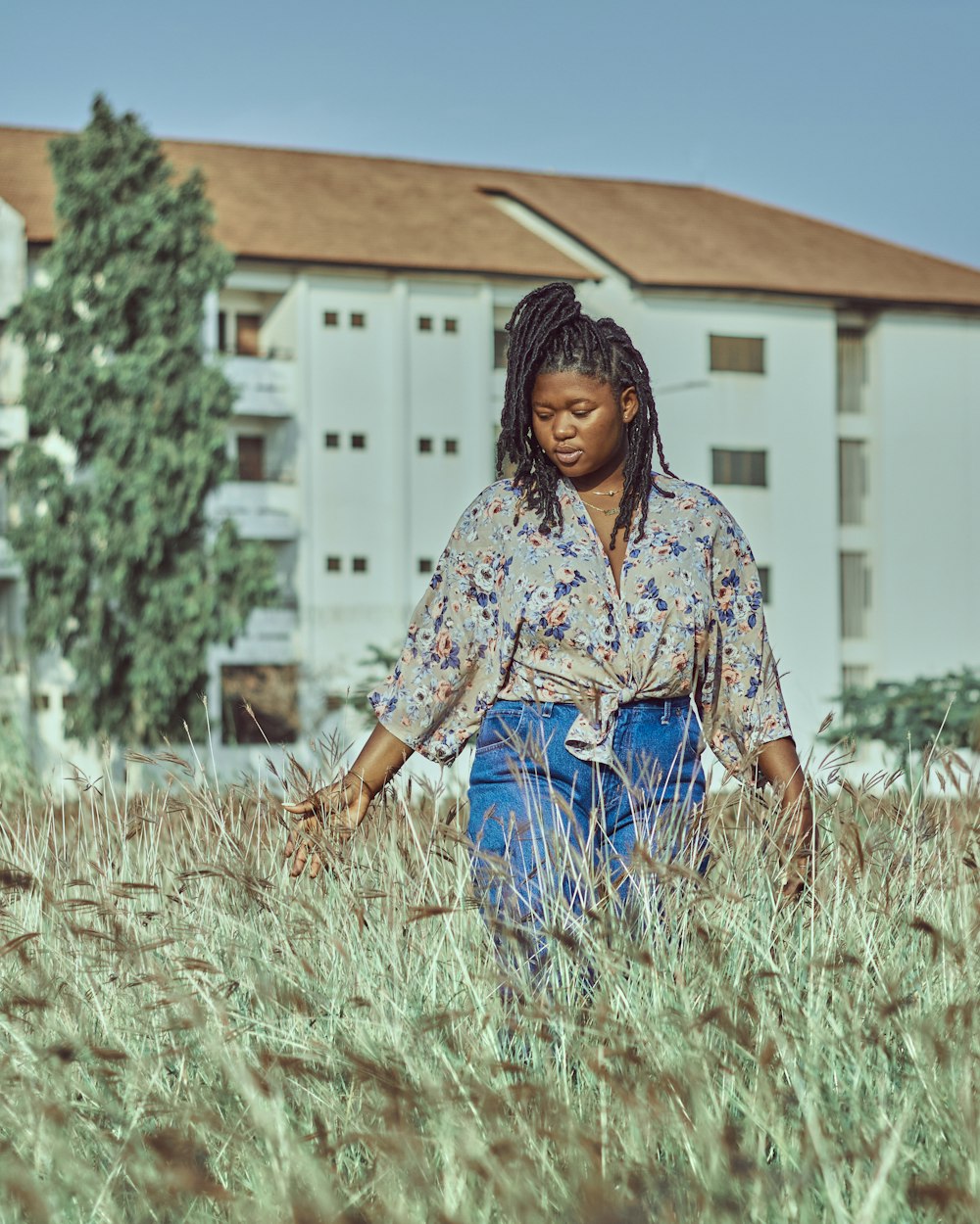 woman in blue denim jeans sitting on brown grass during daytime