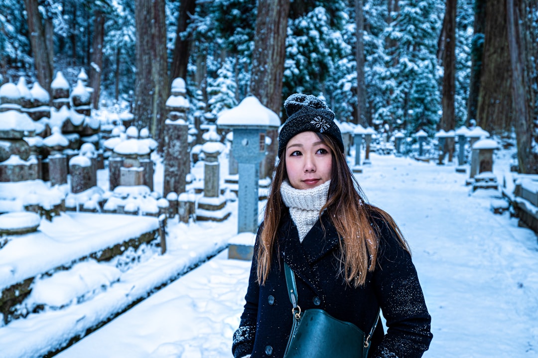 woman in black jacket standing on snow covered ground during daytime