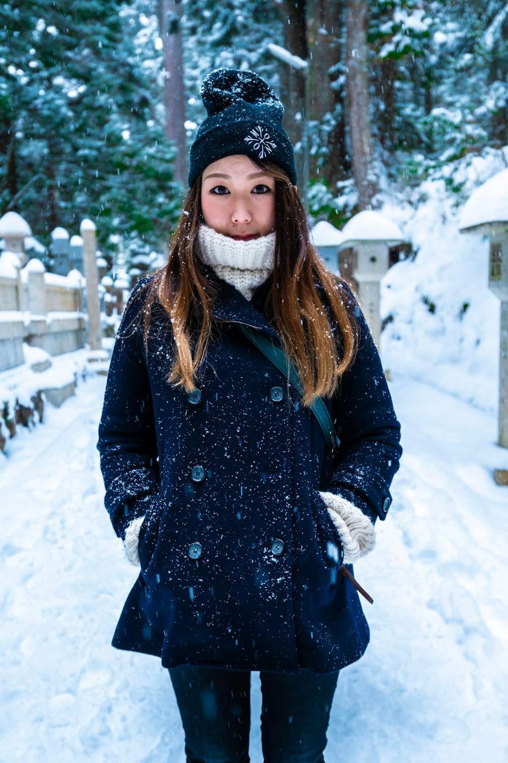 woman in black coat standing on snow covered ground during daytime