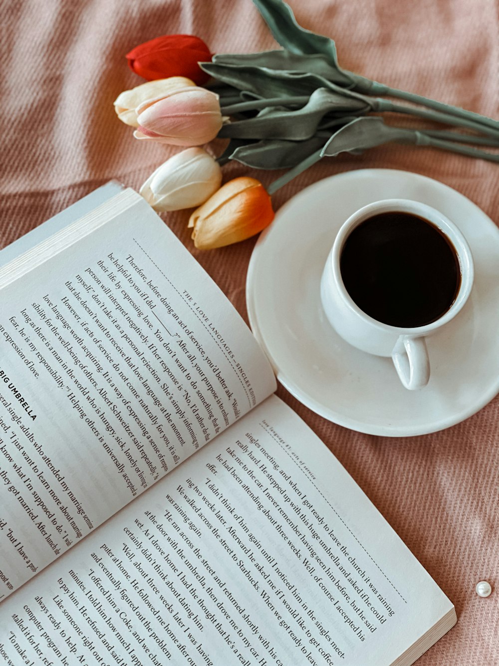 white ceramic mug on white ceramic saucer beside white book page