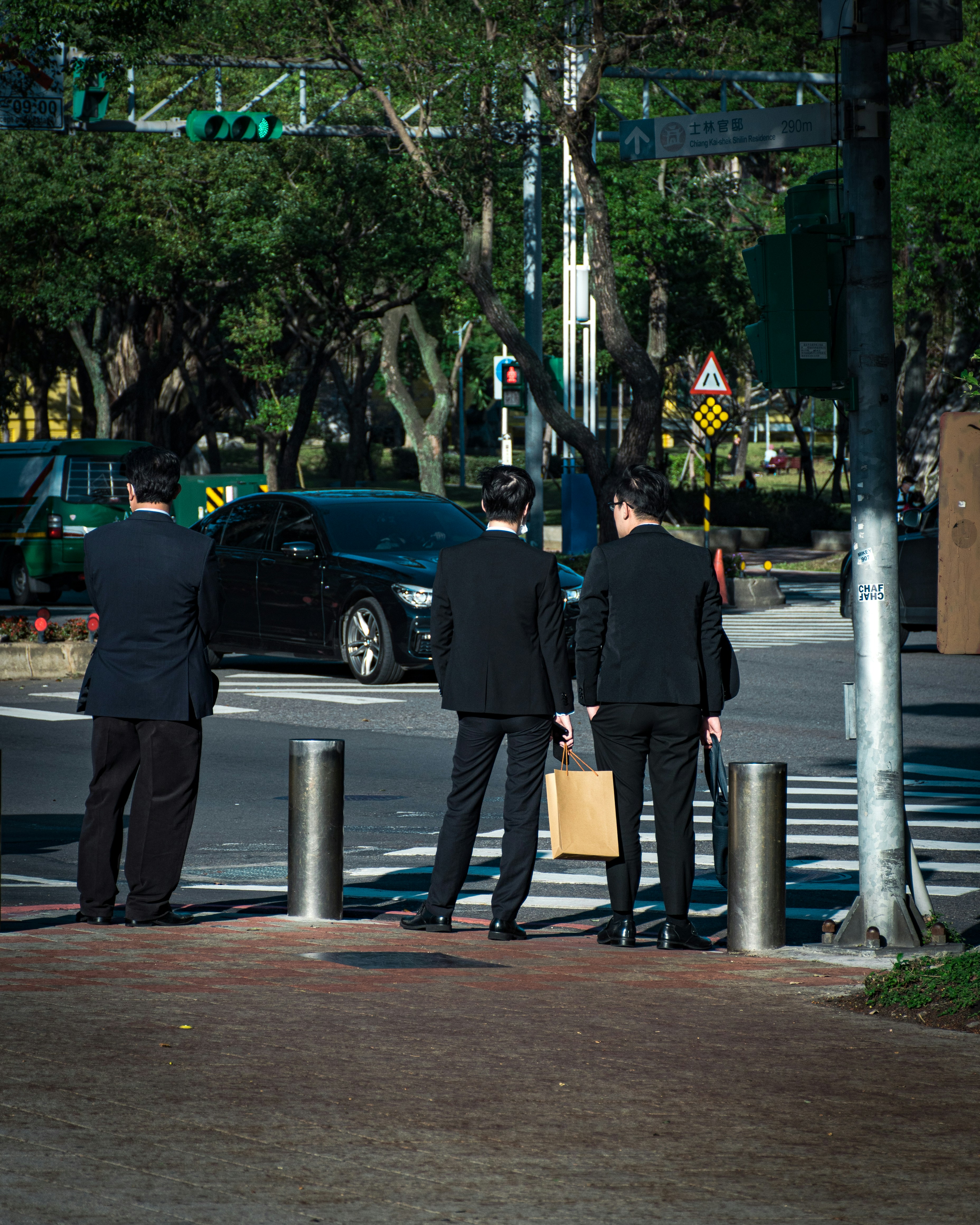man in black jacket and brown pants standing beside black car during daytime