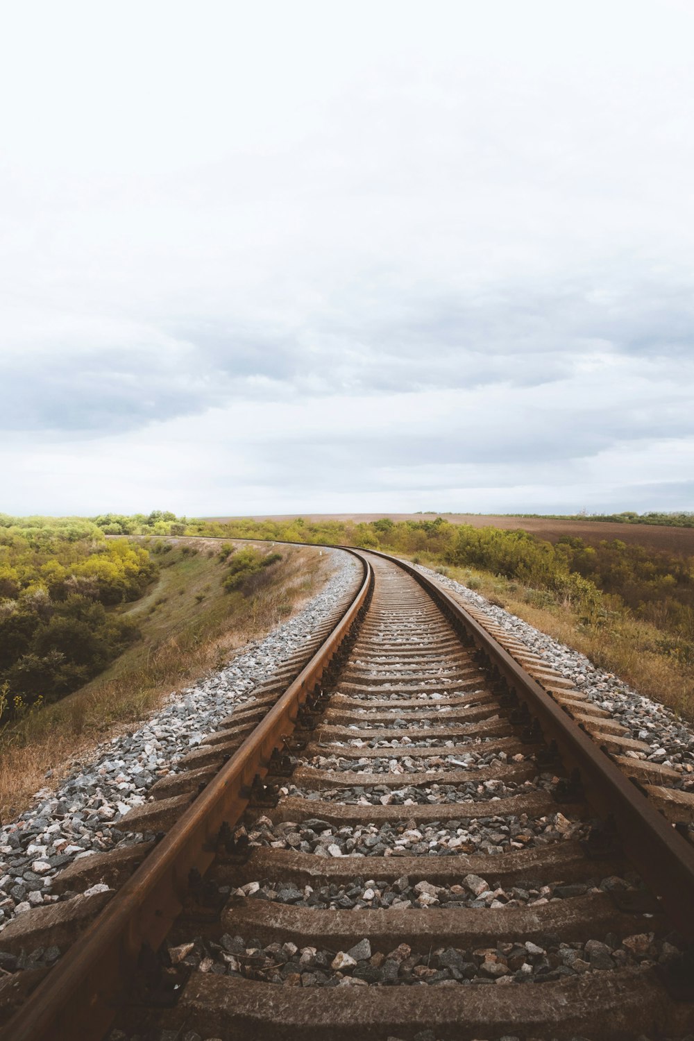 brown train rail under cloudy sky during daytime