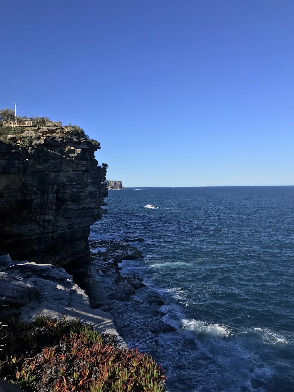 rocky cliff by the sea under blue sky during daytime