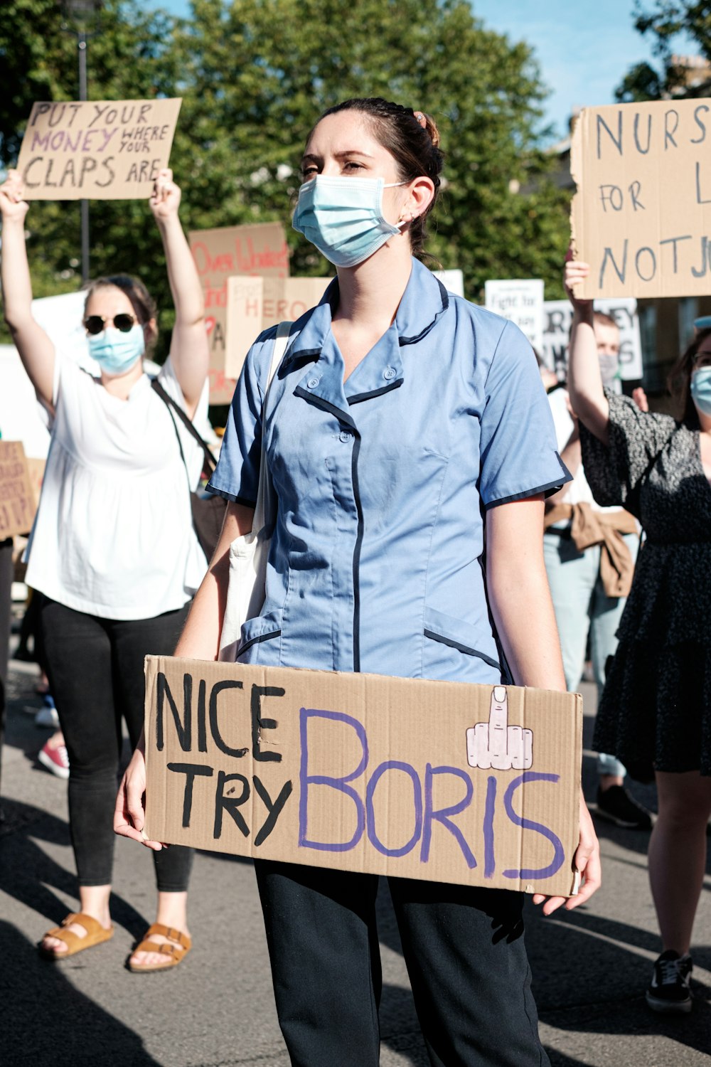 woman in blue button up shirt holding brown wooden signage