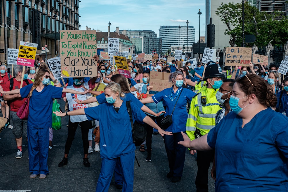 people in blue shirts standing on road during daytime