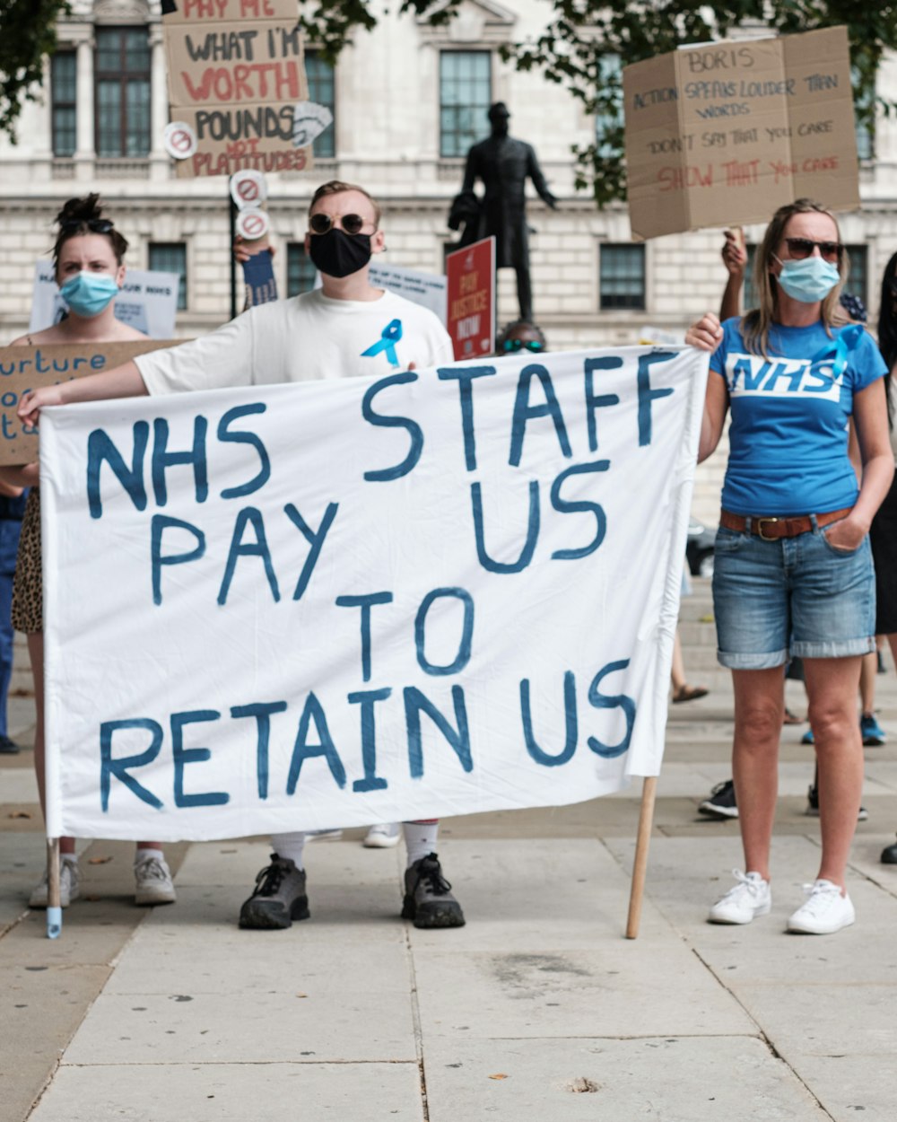 woman in blue shirt holding white and blue banner