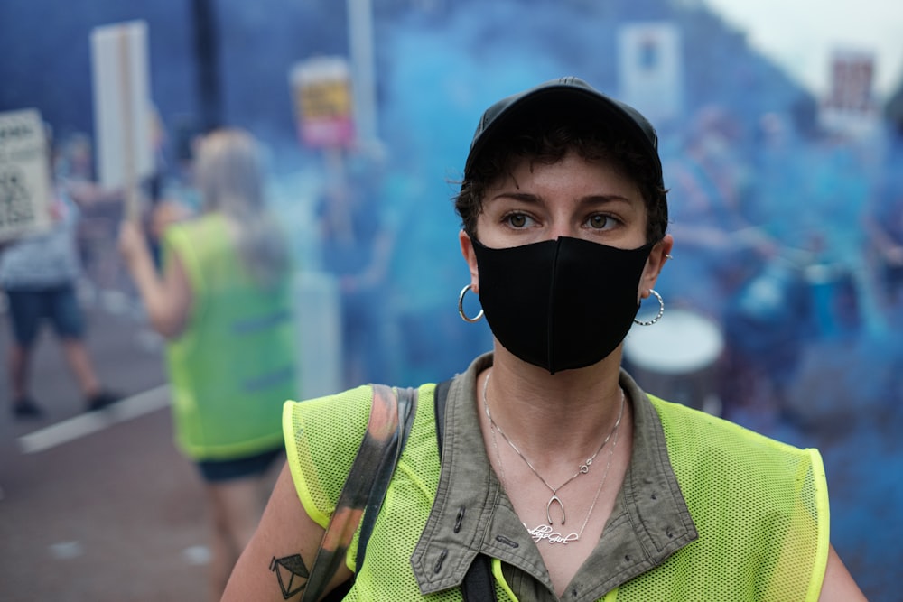 man in green tank top wearing black mask