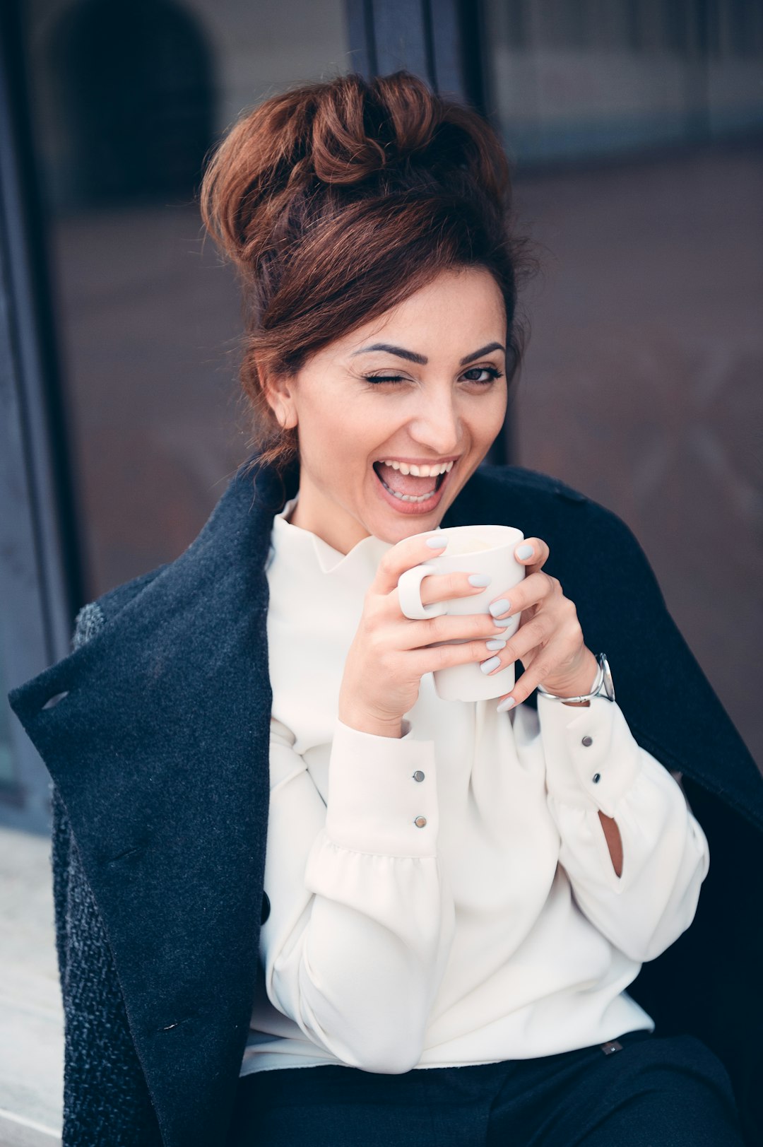 woman holding a coffee cup winking