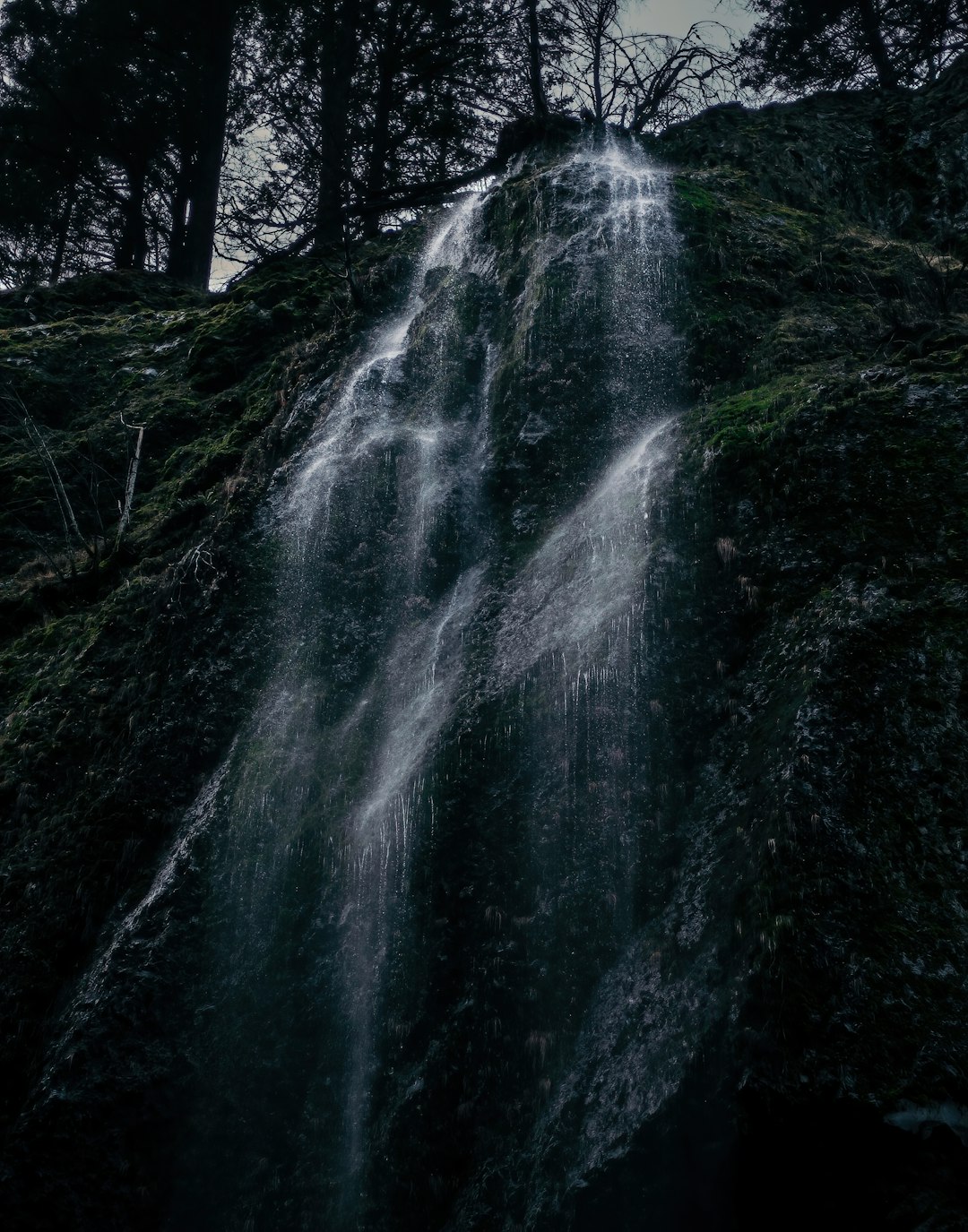 water falls on black and green mountain