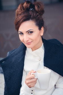woman in black blazer holding white ceramic mug