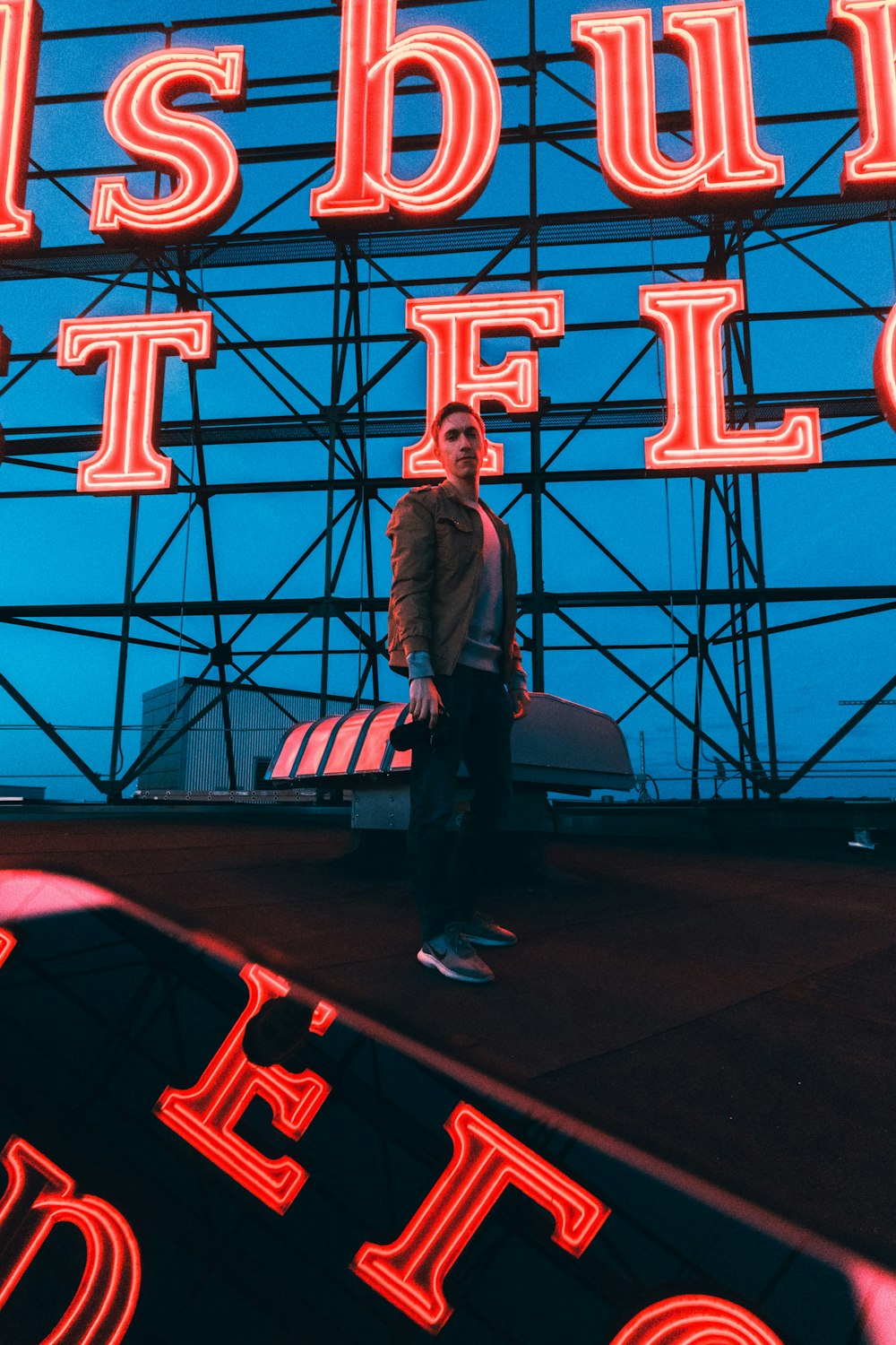 man in black suit standing on red and blue lighted stage