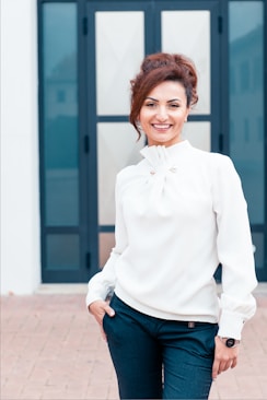 woman in white dress shirt and blue denim jeans smiling