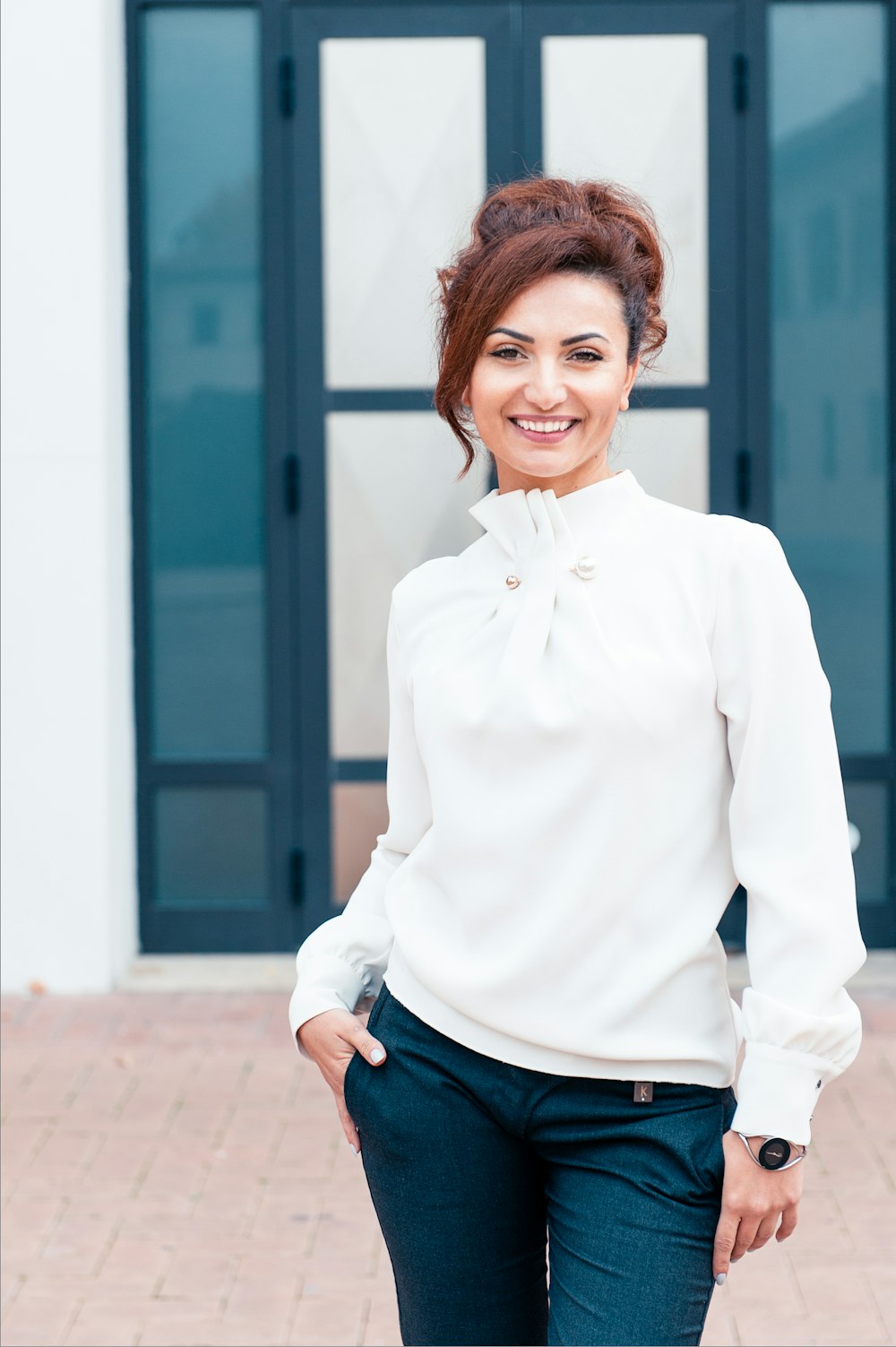 Mujer con camisa de vestir blanca y jeans de mezclilla azul sonriendo