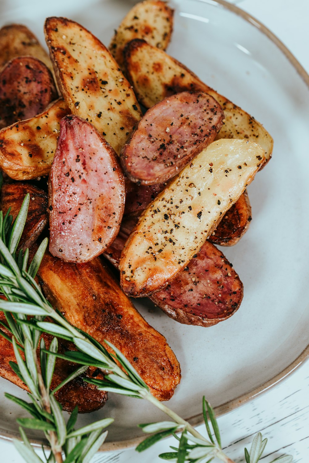 potato wedges on white ceramic plate with rosemary