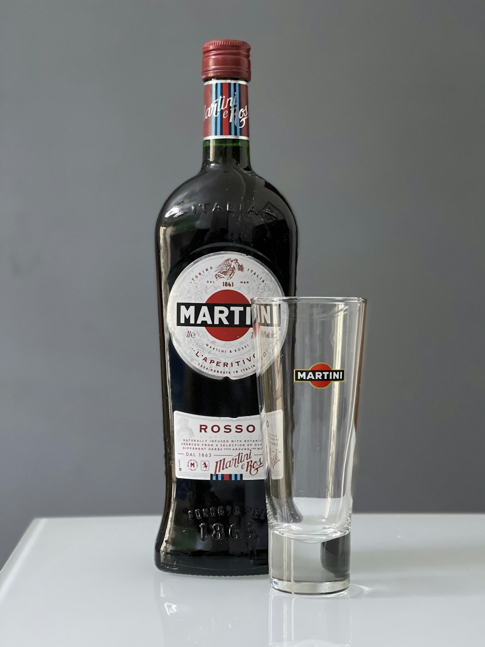 Eine Flasche Martini neben einem Schnapsglas