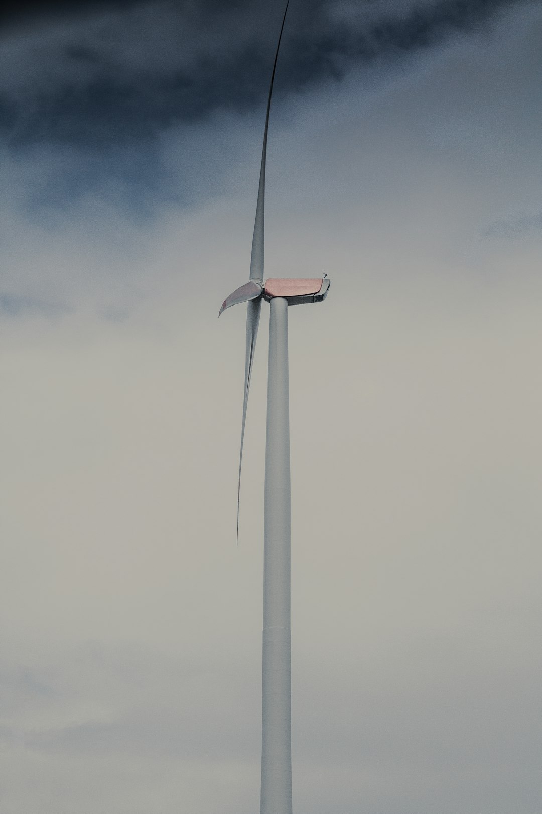 white wind turbine under gray clouds