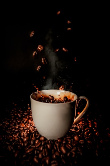 coffee cup with whole beans falling in black coffee