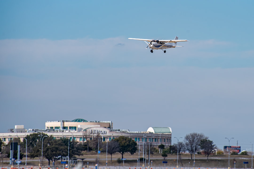 white and red airplane flying over the city during daytime