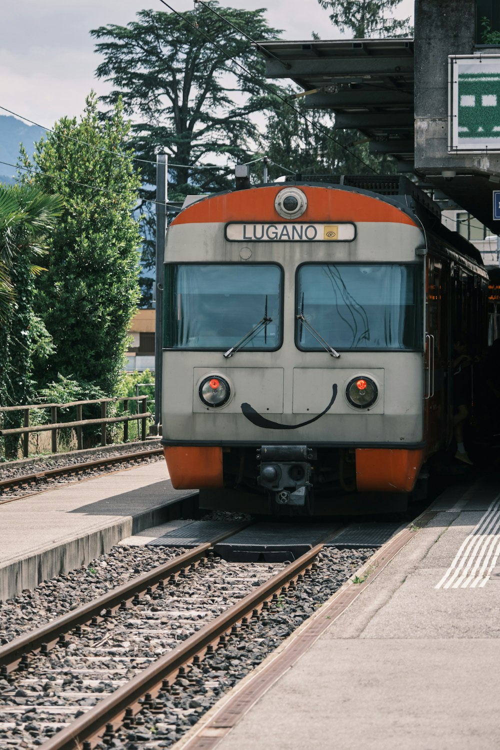 Orange-weißer Zug tagsüber auf Bahngleisen