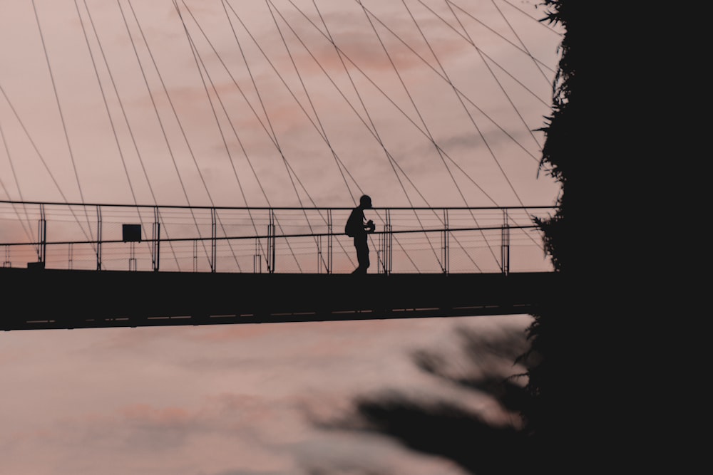 夕暮れ時の橋の上に立つ男のシルエット