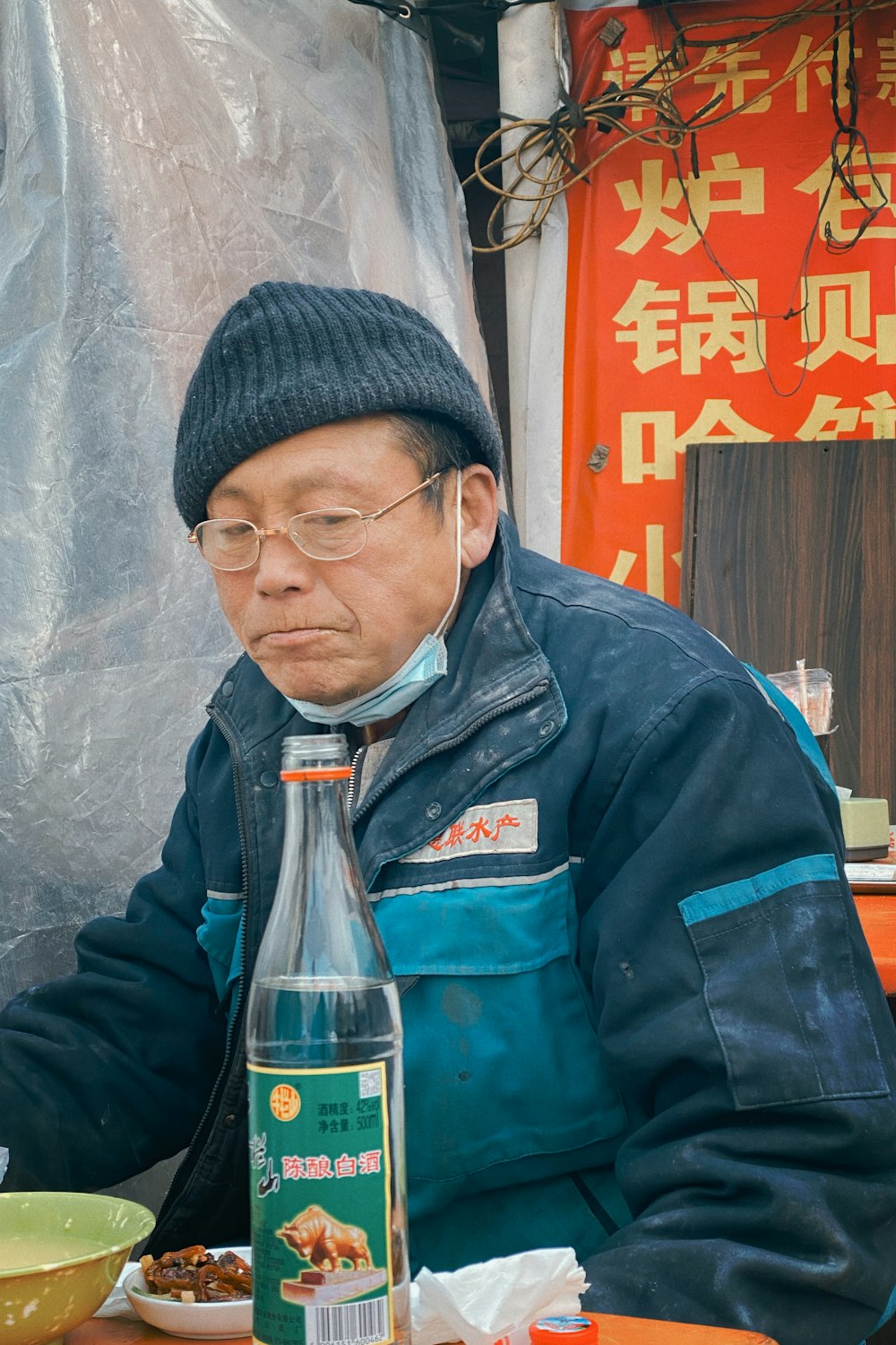 man in green jacket holding coca cola bottle