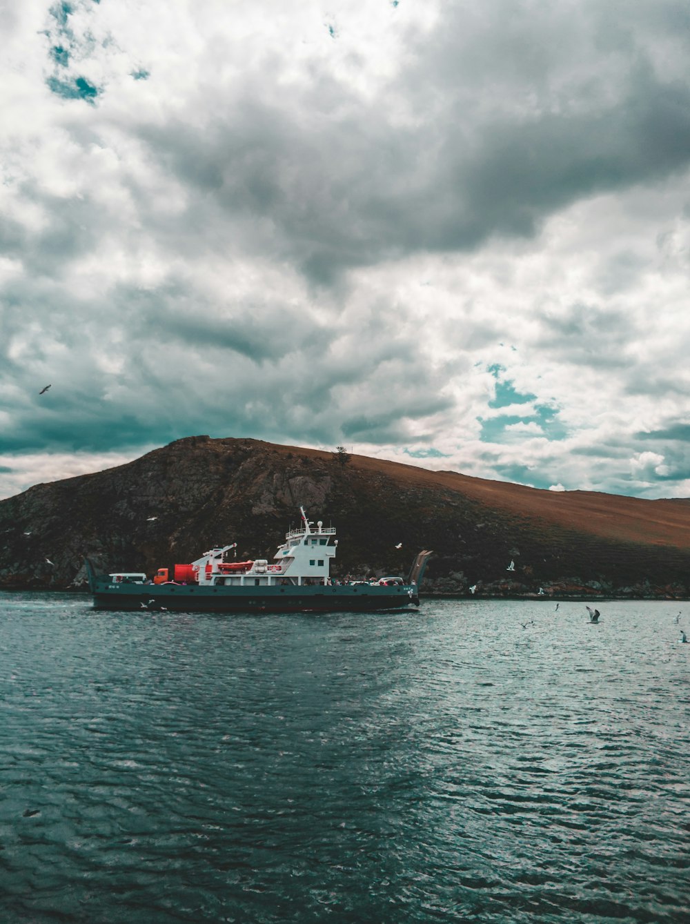 white and red ship on sea under cloudy sky during daytime