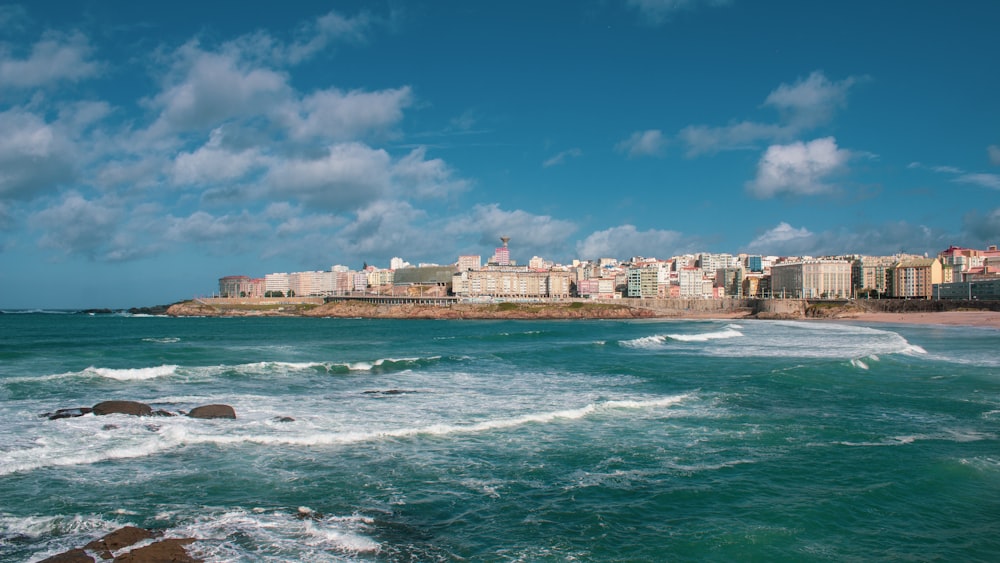 white and brown concrete buildings beside sea under blue sky and white clouds during daytime