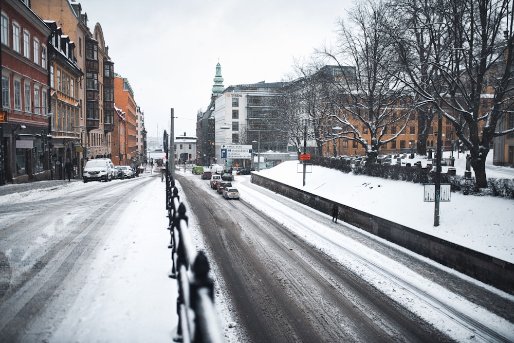 snow covered road between buildings during daytime