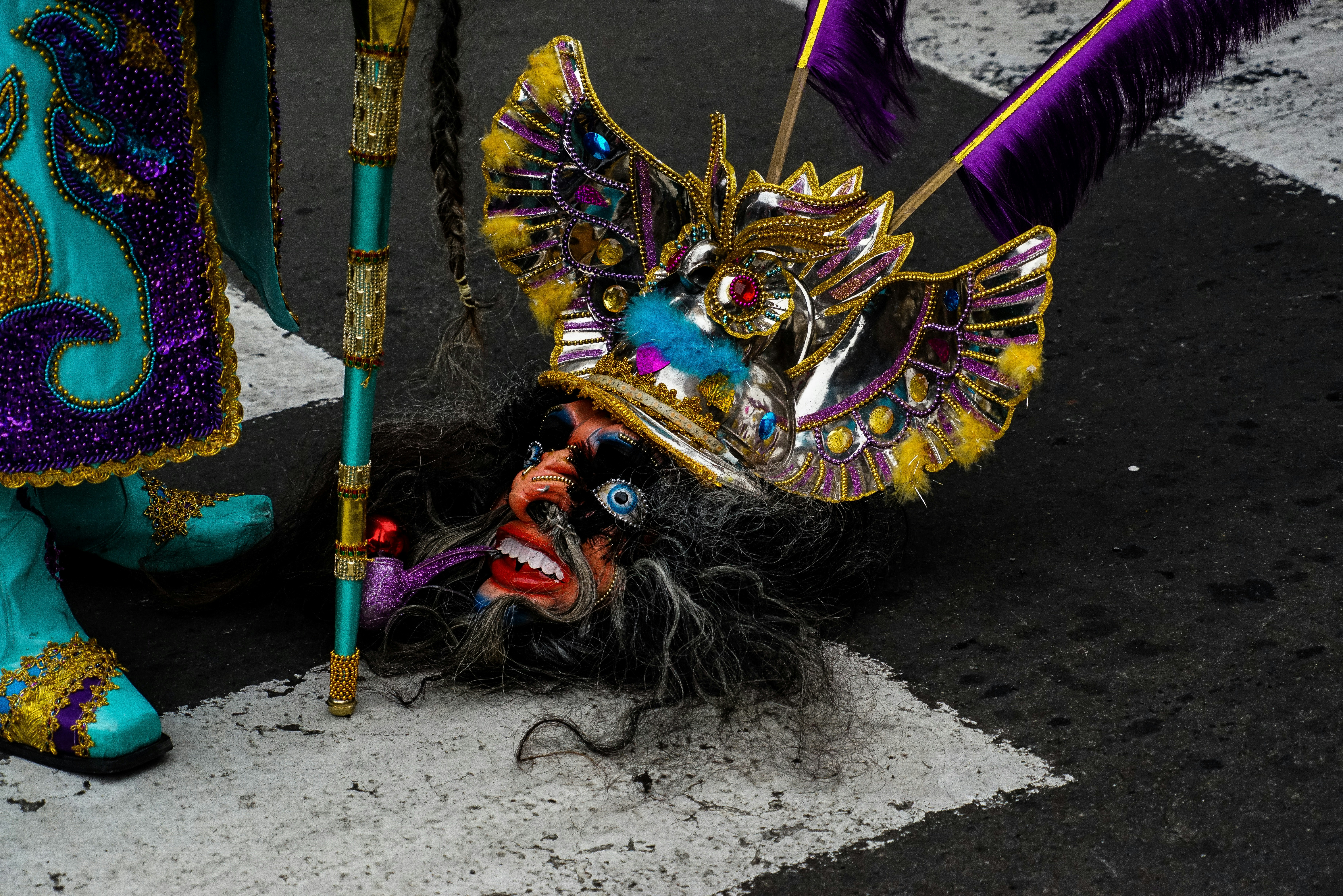 person wearing blue yellow and red feather mask