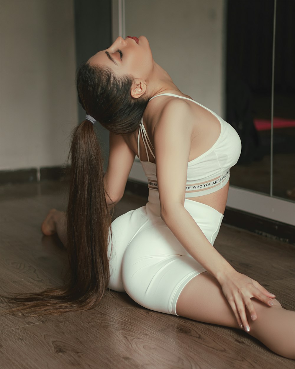 woman in white sports bra and white shorts kneeling on floor