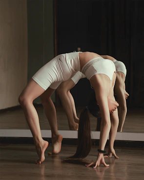 woman in white tank top and white shorts lying on black floor