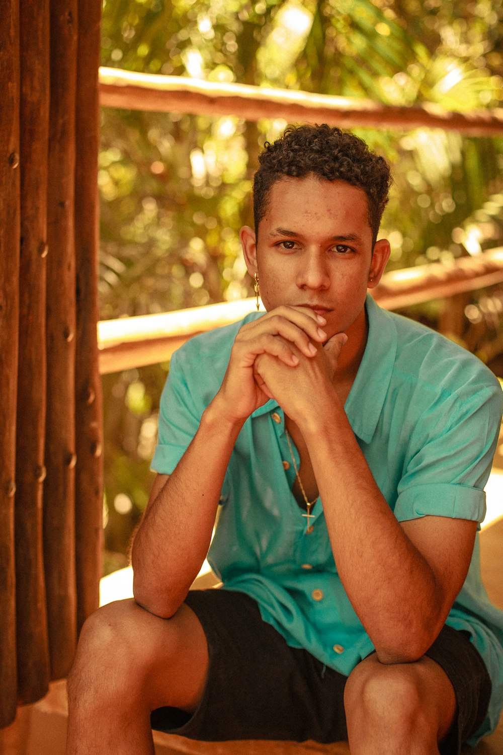 man in teal crew neck t-shirt sitting on brown wooden bench