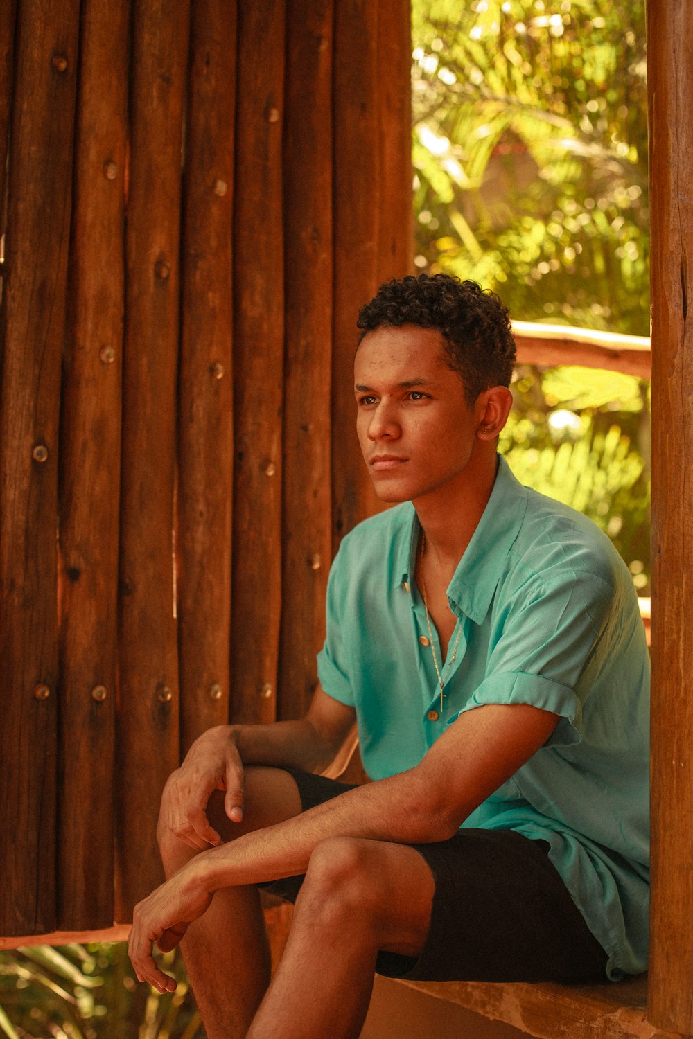 man in green button up shirt sitting on brown wooden bench