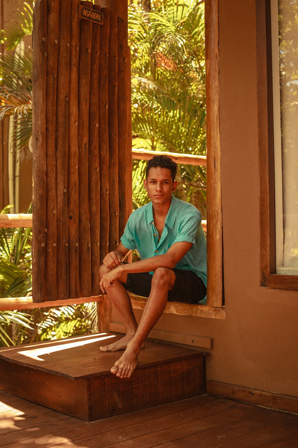 man in teal button up shirt sitting on brown wooden bench