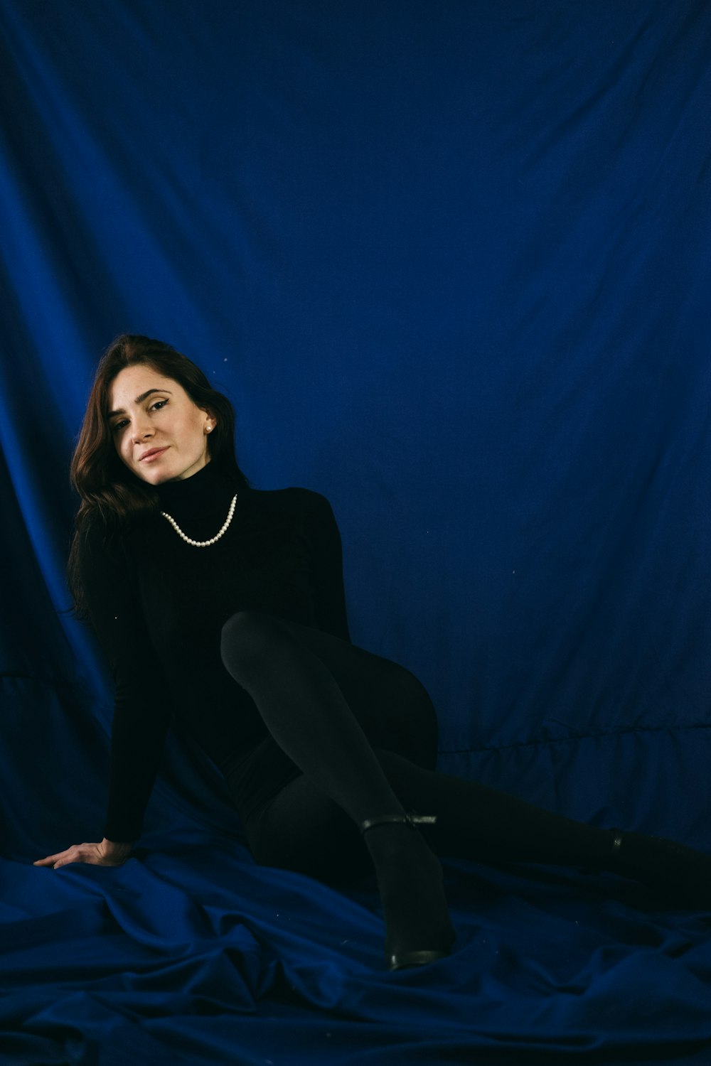 woman in black long sleeve shirt and black pants sitting on blue textile