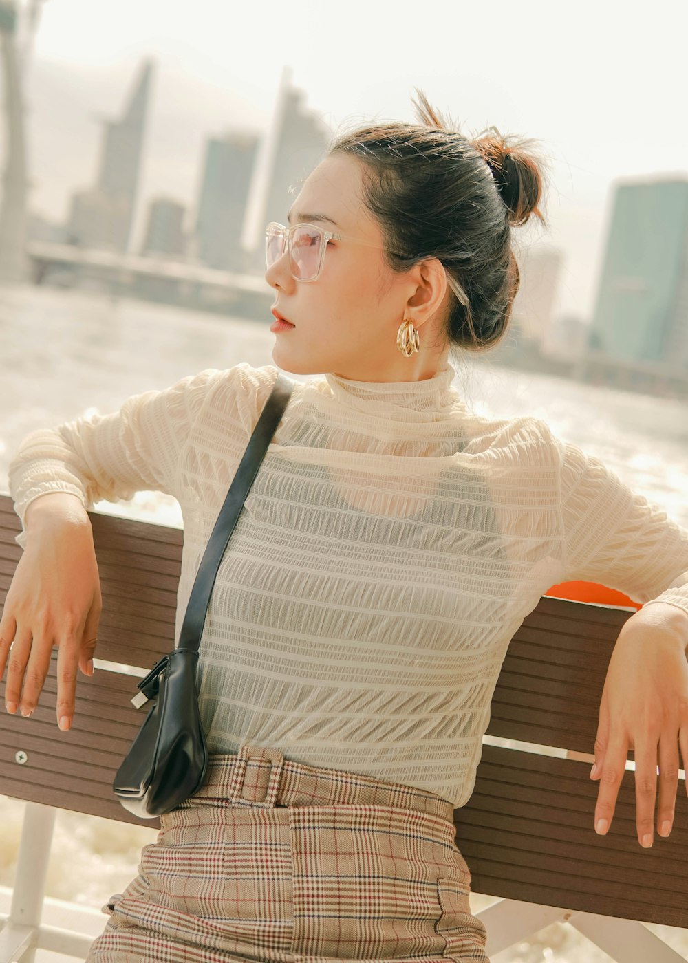 Femme en chemise blanche à manches longues assise sur un banc en bois marron