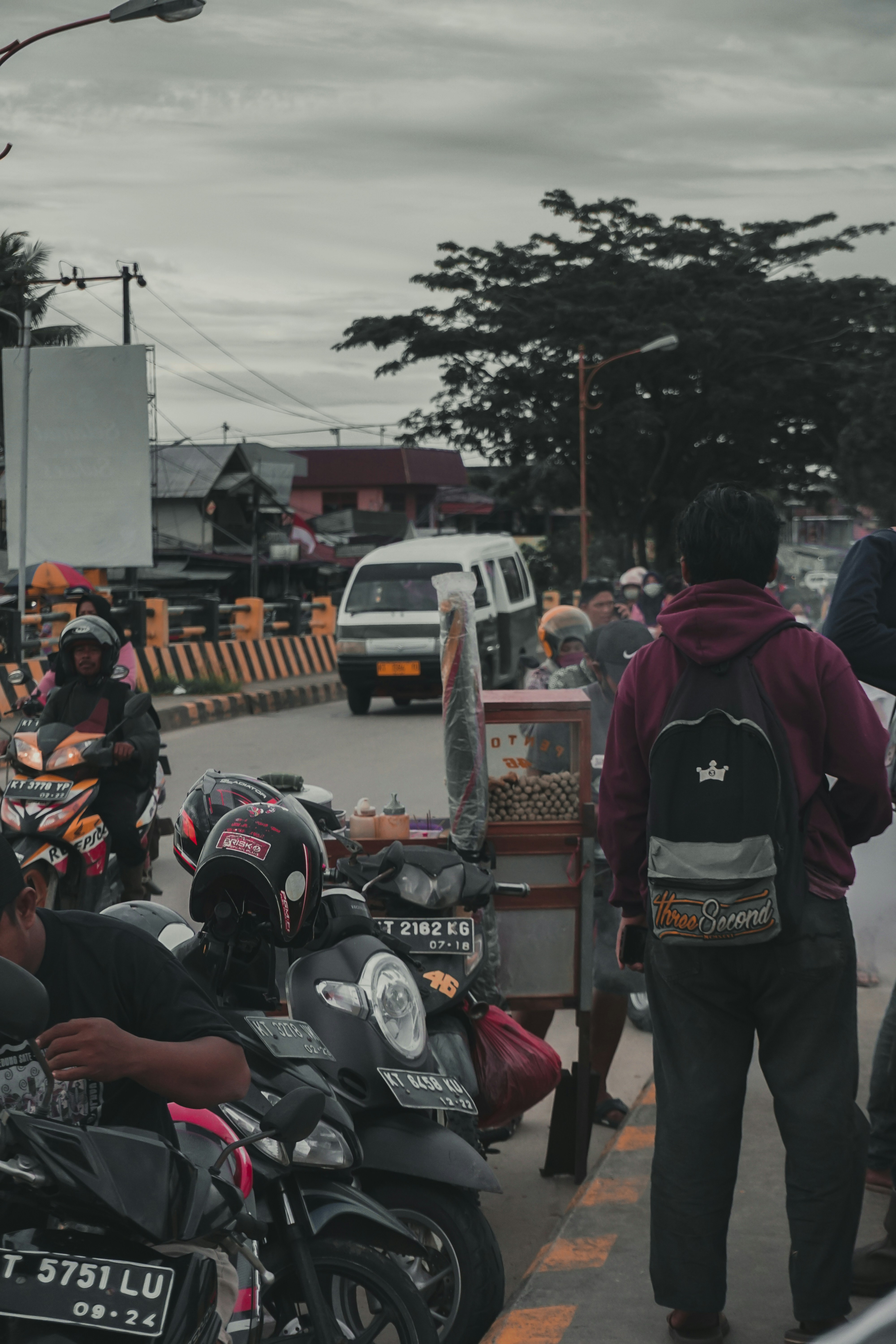 Orang-orang dengan jaket hitam dan merah berdiri di jalan pada siang hari