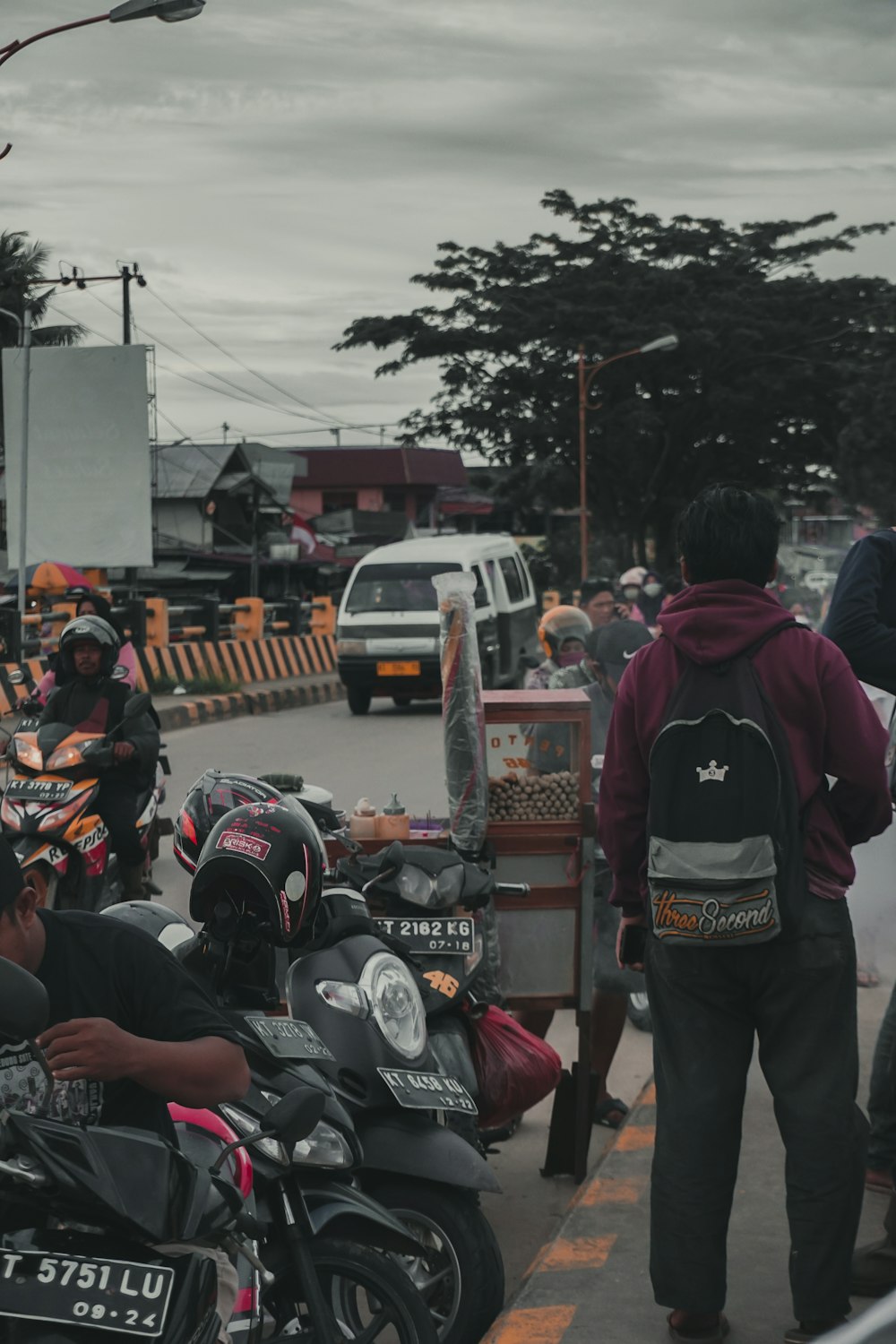 people in black and red jacket standing on road during daytime