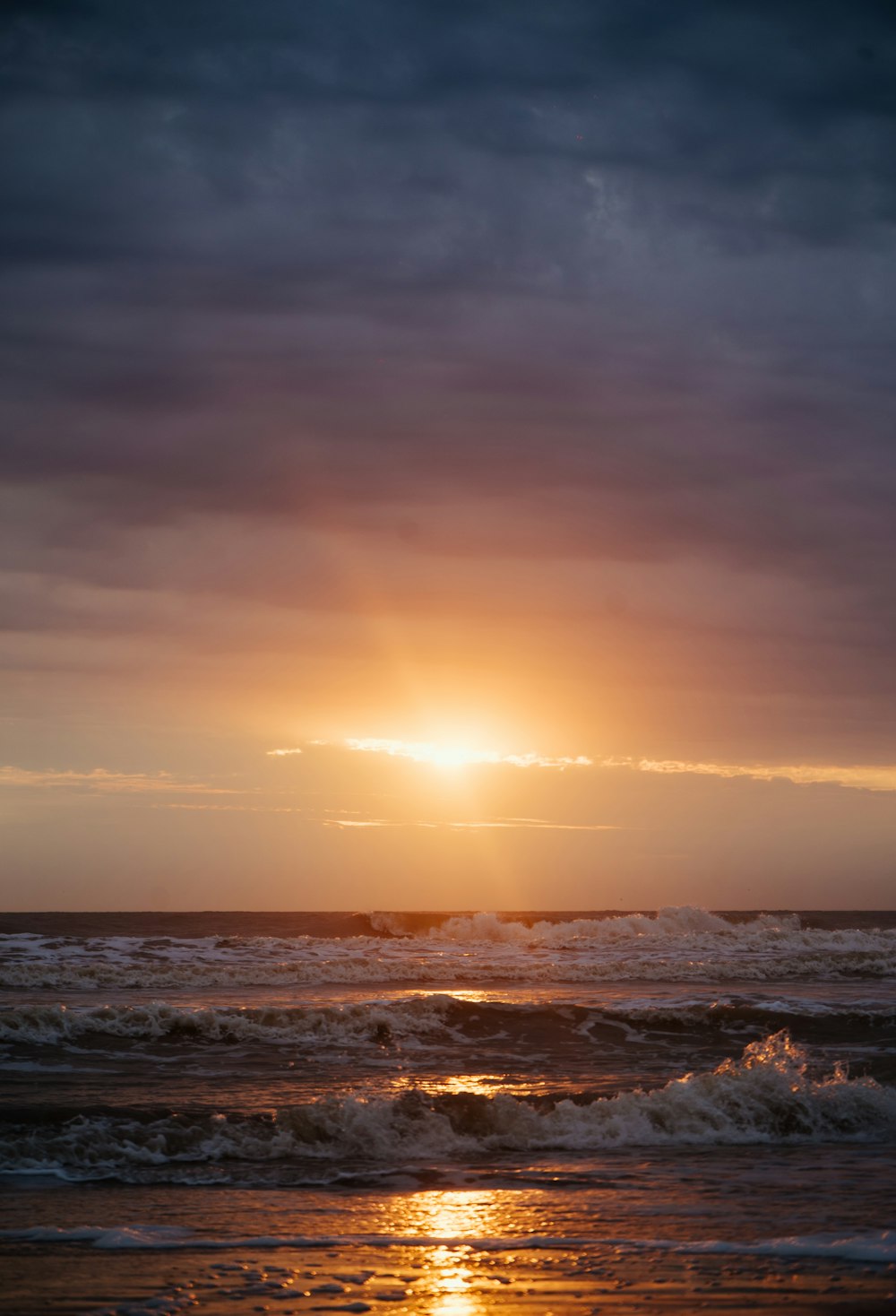 ocean waves crashing on shore during sunset