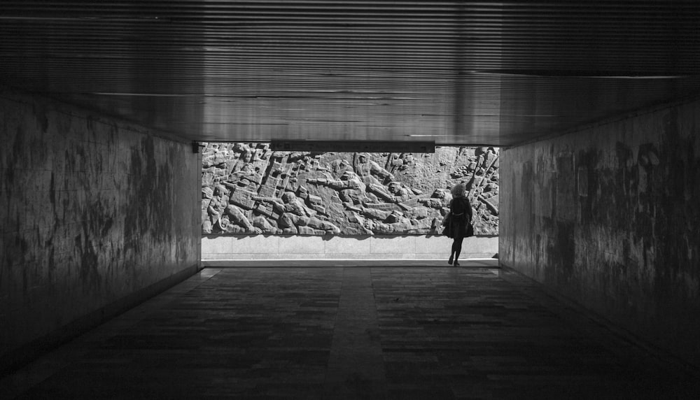 grayscale photo of woman walking on wooden floor