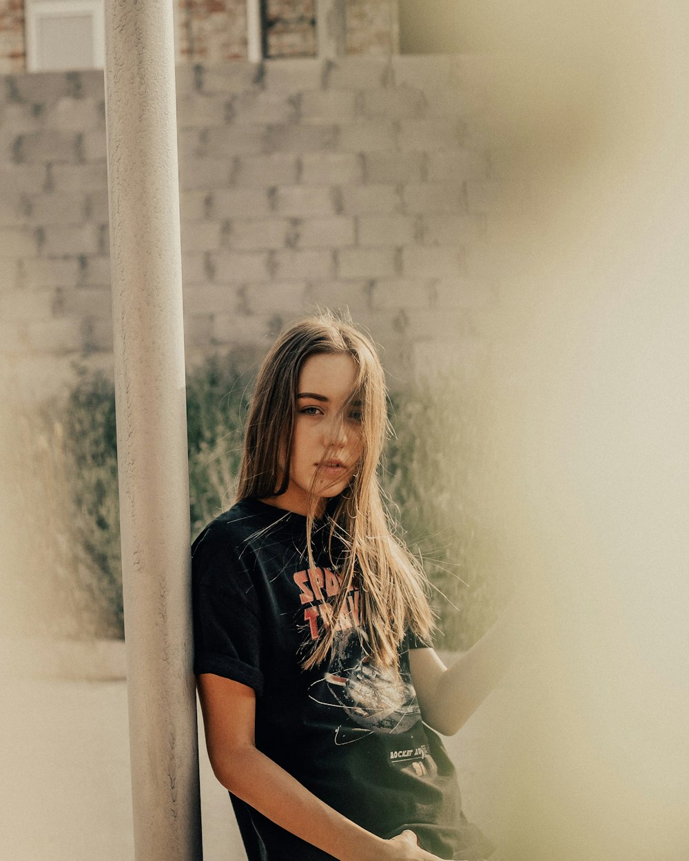 woman in black crew neck t-shirt leaning on white concrete post