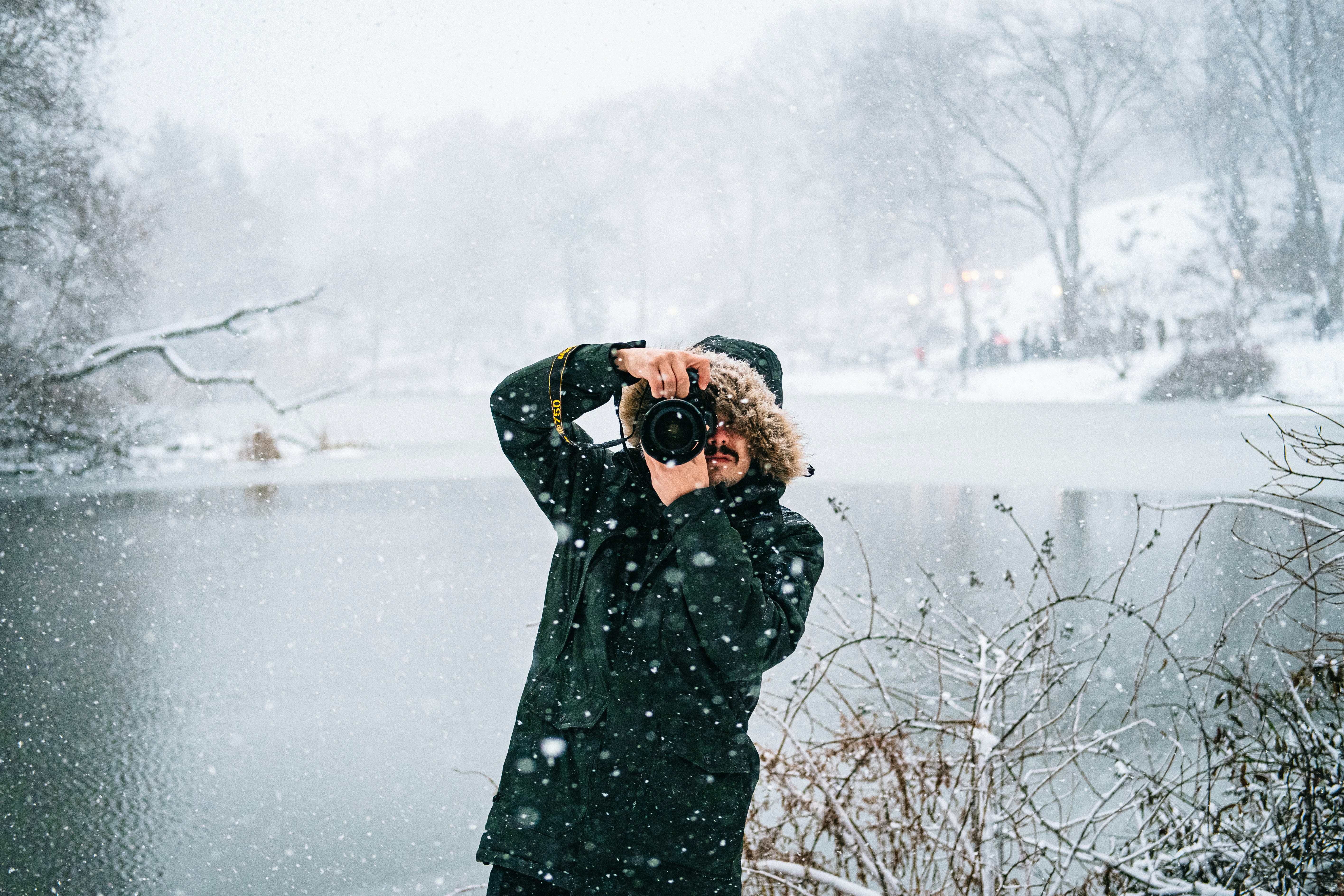person in black coat holding black camera