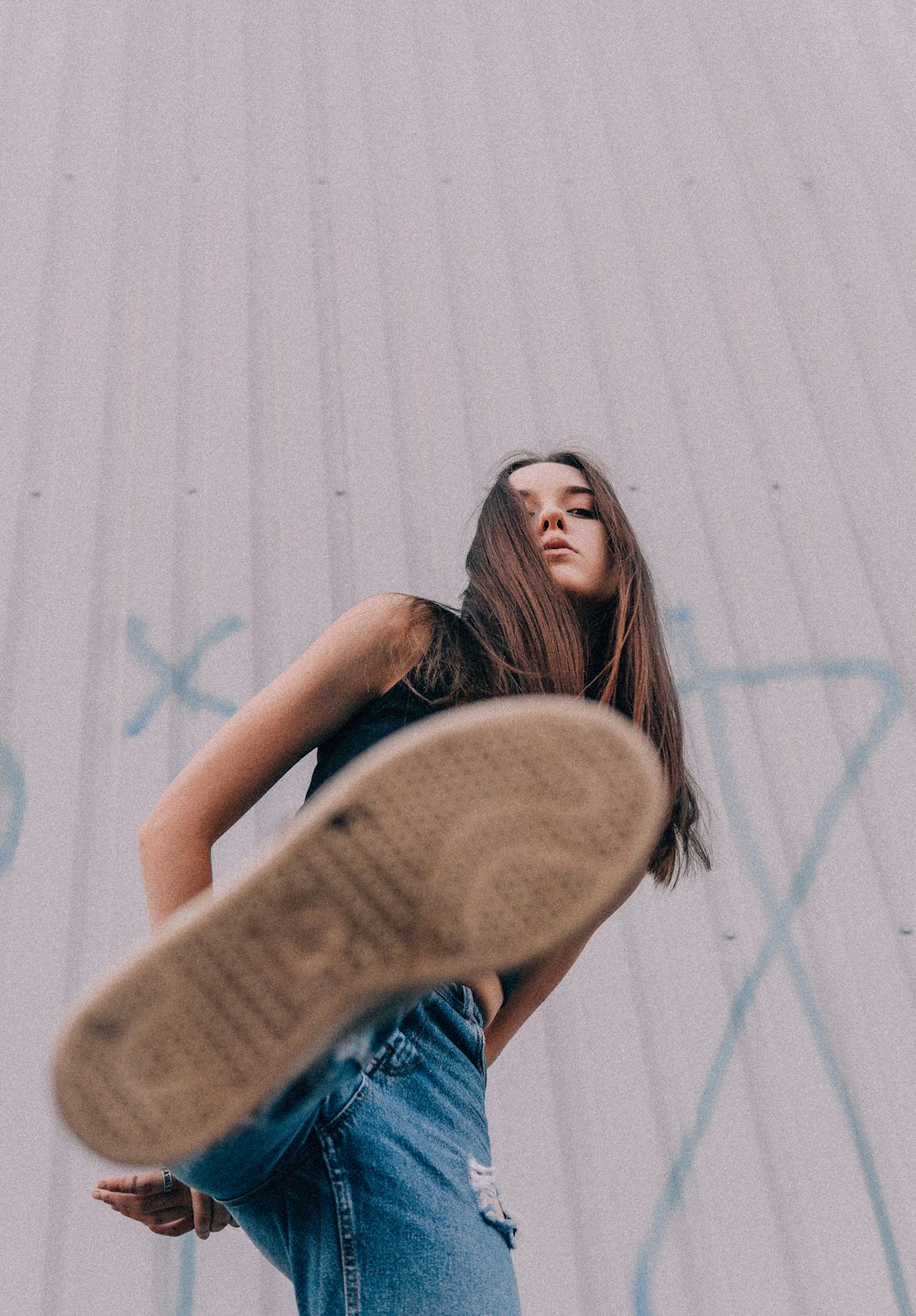 woman in blue denim shorts leaning on white wall