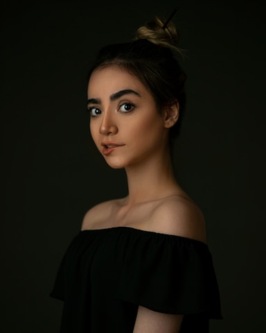 A softly lit portrait of a model in a dark, elegant setting, embodying confidence and grace.