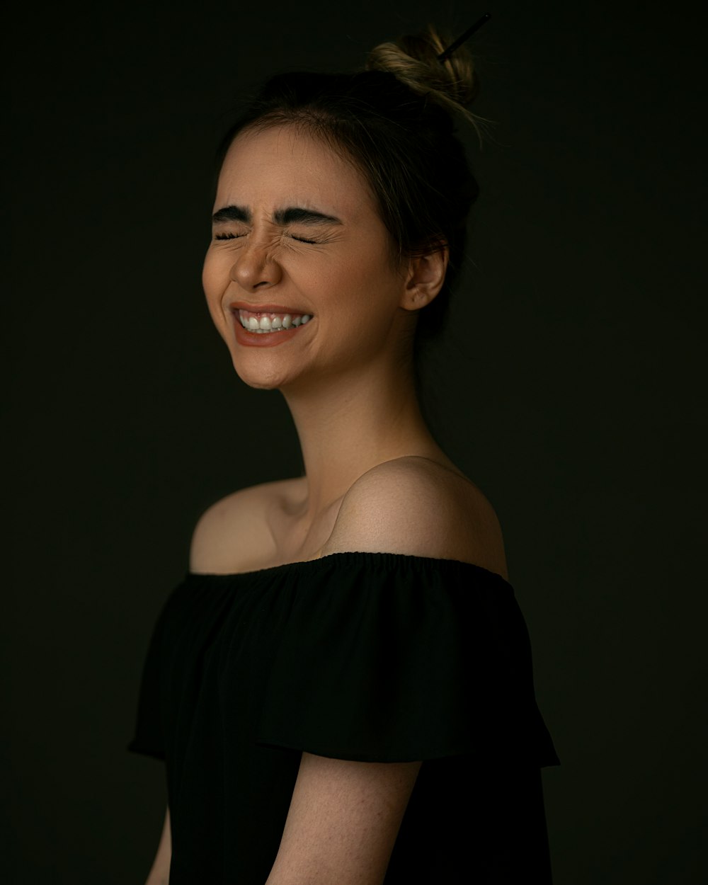woman in black off shoulder dress smiling