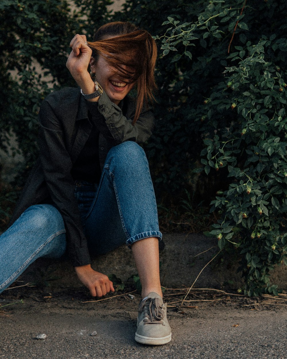woman in black jacket and blue denim jeans sitting on ground