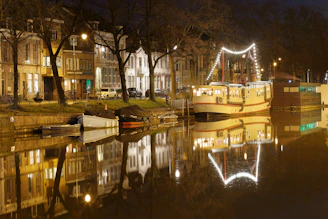 A cozy canal boat lit by soft evening lights, cruising past glowing bridges and reflections.