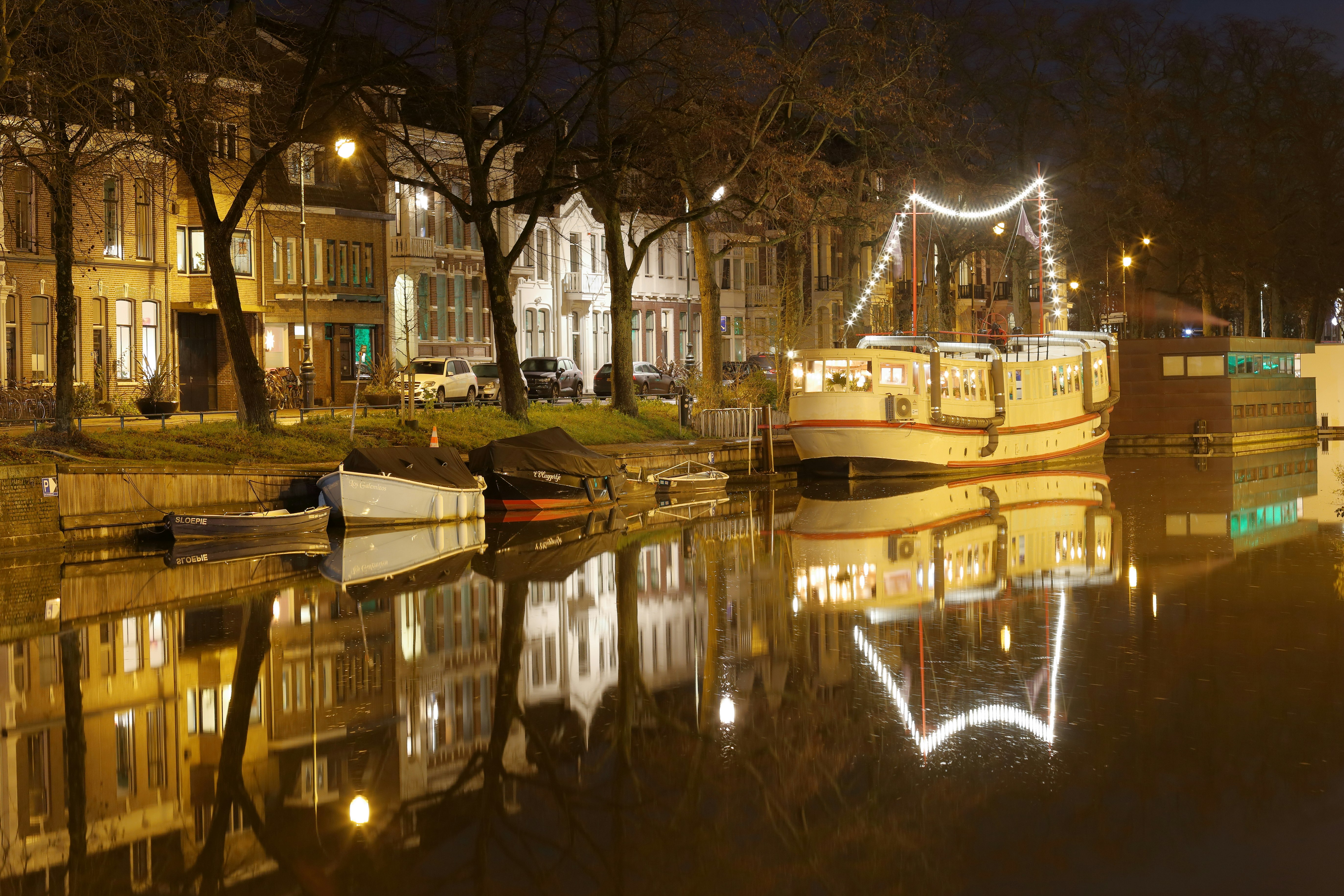 white boat on water near bare trees during night time