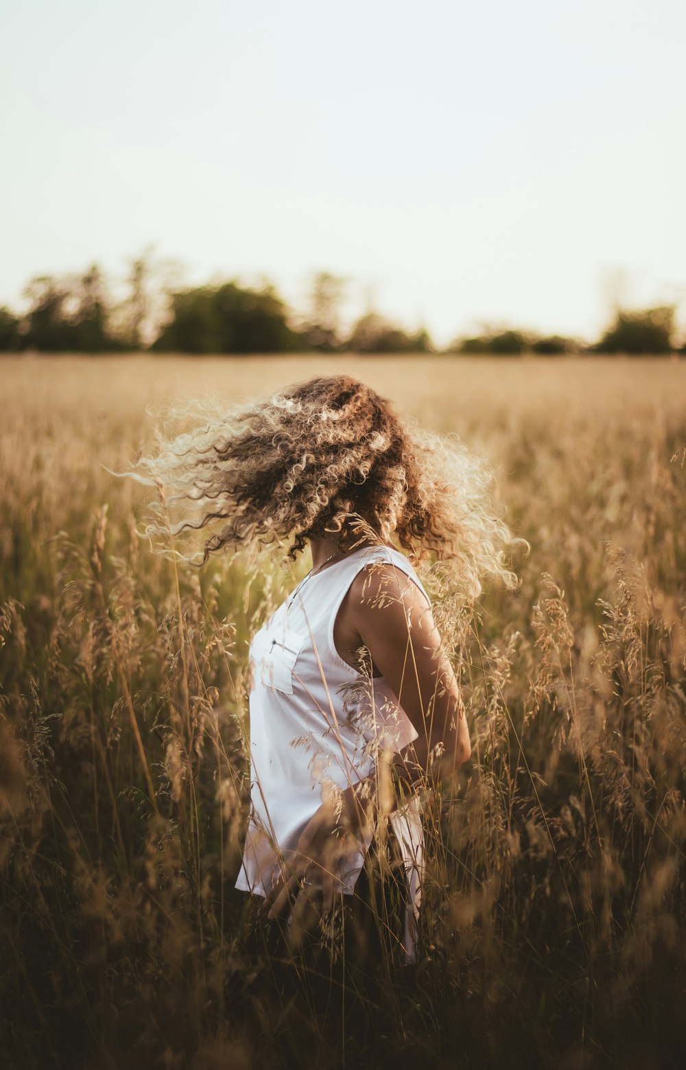 woman in white shirt standing on brown grass field during daytime