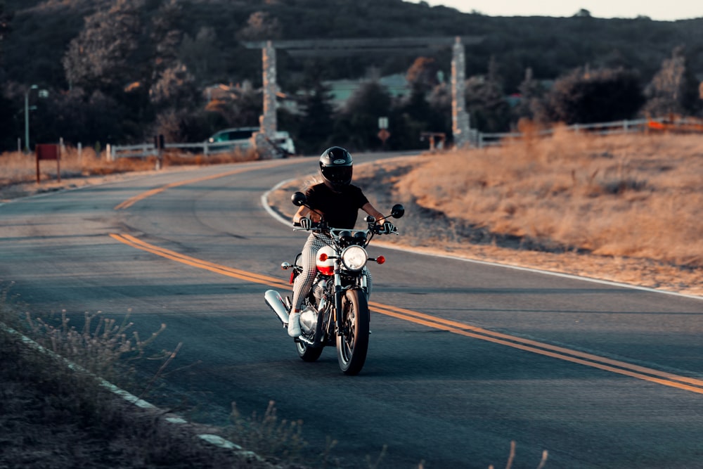 昼間の道路でバイクに乗る黒いジャケットの男